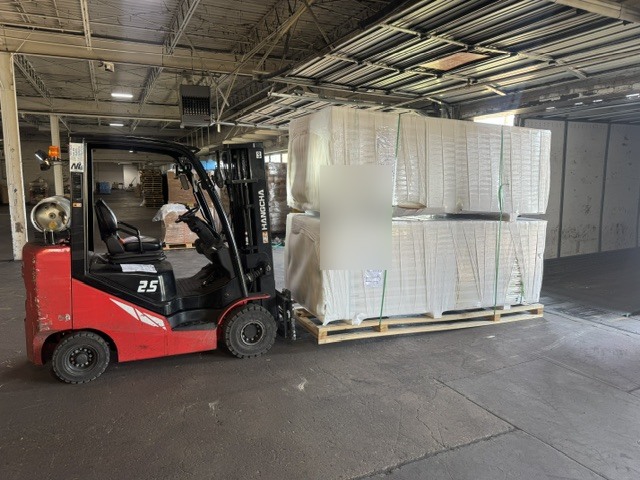 NOW Logistics forklift staging wrapped freight during a van-to-flatbed transload